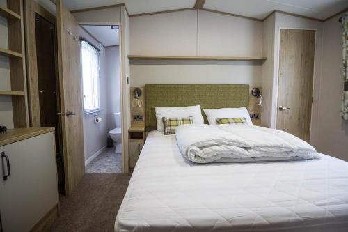 a bedroom with a large white bed and a bathroom at Beautiful 6 Berth Caravan With Decking At Southview Holiday Park Ref 33024o in Skegness