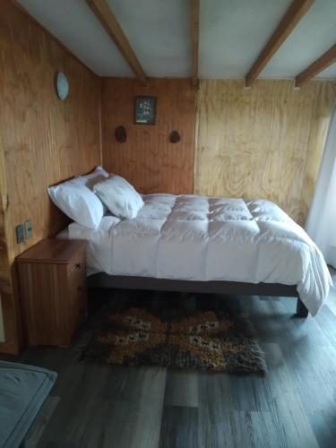 1 dormitorio con 1 cama y suelo de madera en Cabañas Quito, en Compu