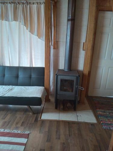 a fireplace in a room with a couch and a stove at Cabañas Quito in Compu