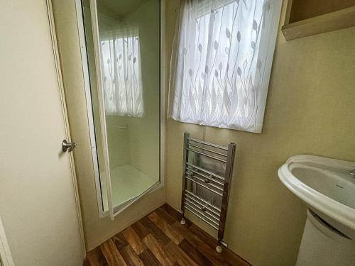 a bathroom with a shower and a sink and a mirror at Caravan At Highfield Grange With Decking, Sleeps 6 Ref 26446ba in Clacton-on-Sea