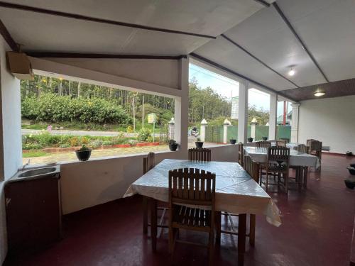 a restaurant with tables and chairs and large windows at The Green Savanna Holiday Bungalow Nuwara Eliya in Nuwara Eliya