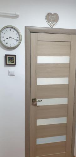 a wooden door with a clock on the wall at Hellen Apartament in Târgovişte