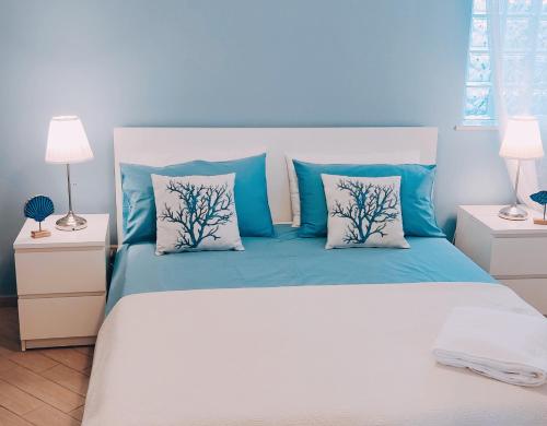 サンタ・テレーザ・ディ・リーヴァにあるLe sorelleのベッドルーム1室(青と白の枕が備わるベッド1台付)