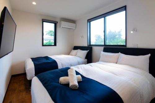 two beds in a room with two bedsitures at The Villa Miyako in Hirara