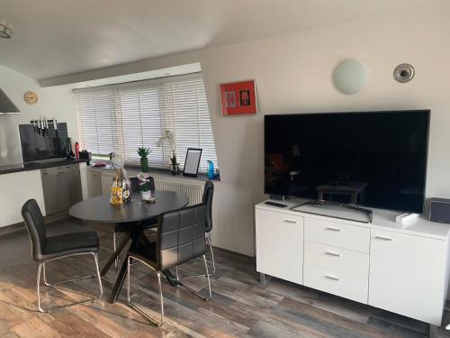 a kitchen with a table and a large screen television at Amsterdam Countryside met Airco ,Geweldig uitzicht, luxe keuken,wasmachine,droger,gratis fietsen in Den Ilp