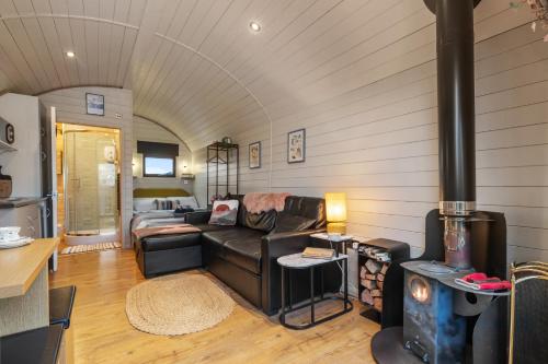 a living room with a couch and a wood stove at Blaenplwyf Luxury Countryside Shire Pods with Hot Tubs in Lampeter
