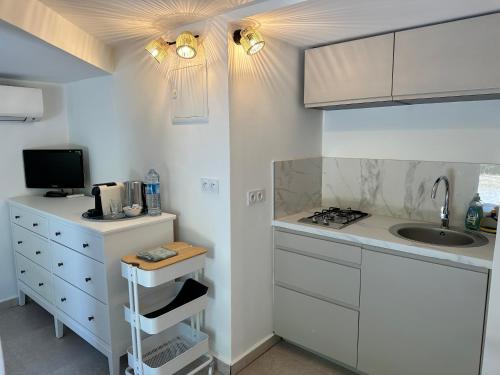 La cuisine est équipée de placards blancs, d'un évier et d'un comptoir. dans l'établissement Magnifique Studio Tropézien à 300 m de la plage (parking gratuit), à Saint-Tropez