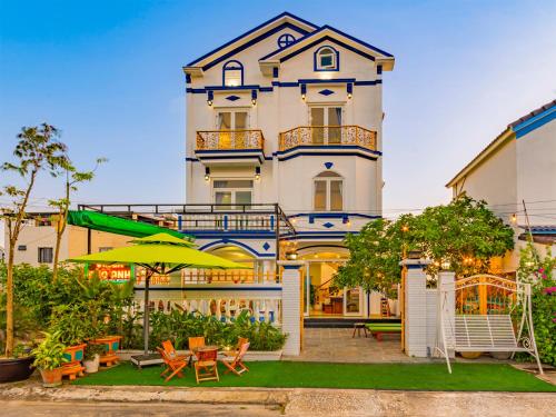 a large building with a patio with chairs and an umbrella at HA An Bang Pool Villa in Hoi An