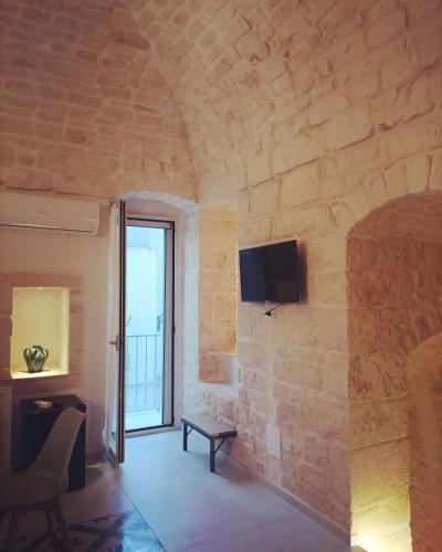 a living room with a tv on a stone wall at Casa Munna in Ceglie Messapica