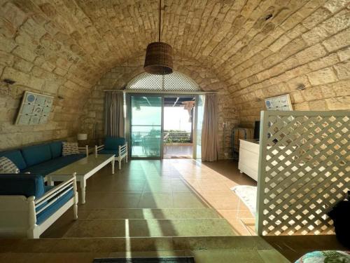 a living room with a couch and a stone wall at Le Blanc Bleu in Jbeil