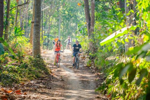 a group of people riding bikes down a dirt trail at Katiliya Park Villa in Mae Chan