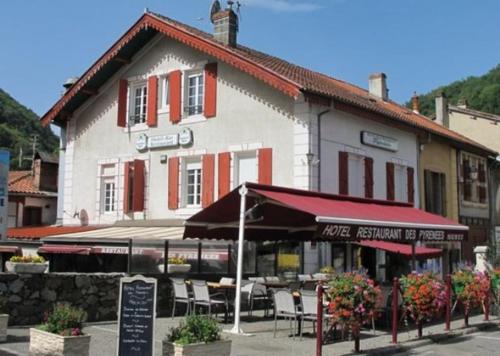 un bâtiment avec des tables et des chaises devant lui dans l'établissement Petit village authentique, à Mauléon-Barousse