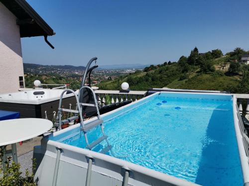a swimming pool on the balcony of a house with a mountain at Panorama Apartman in Molvice