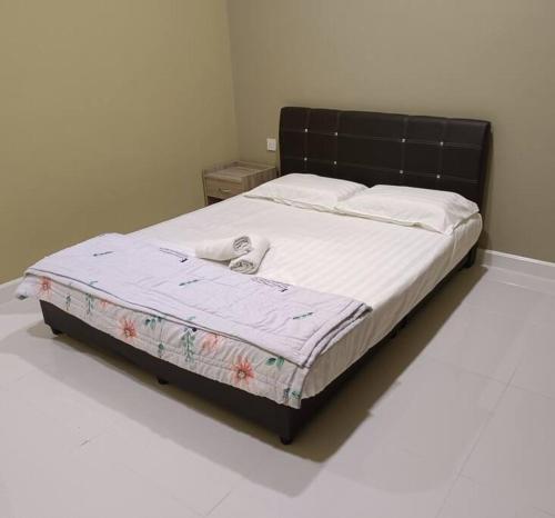 Guesthouse 26 Villa/Sejati/Mile7 في سانداكان: سرير مع اللوح الأمامي الأسود في غرفة النوم