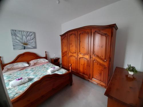 a bedroom with a wooden bed and a wooden cabinet at Dolce casa spiaggia&relax in Lotzorai
