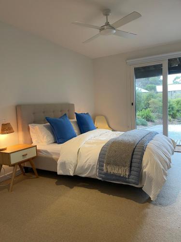 a bedroom with a bed with blue pillows and a ceiling fan at Sunrise @ Breakers in Lorne