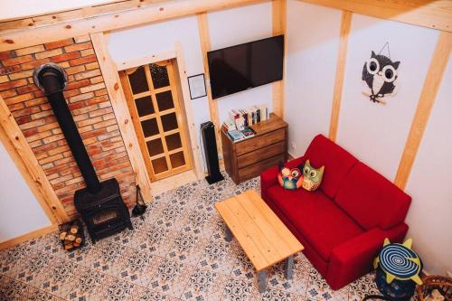 sala de estar con sofá rojo y chimenea en Domek Sówka na Kociewiu 