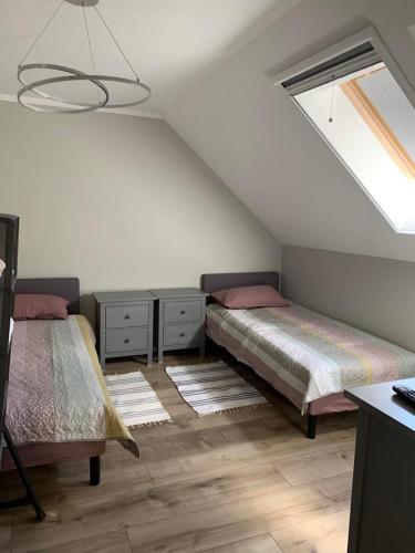 een slaapkamer op zolder met 2 bedden en een raam bij Dom na Mazurach in Stare Juchy