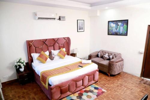 a bedroom with a large bed and a chair at Divine India Service Apartment 3Bhk 1B Saket in New Delhi