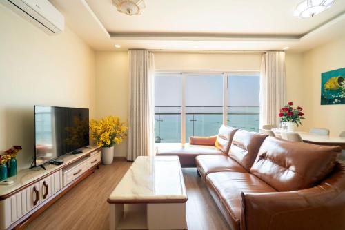 a living room with a leather couch and a television at Sapphire Residence 2411 Ha Long in Ha Long