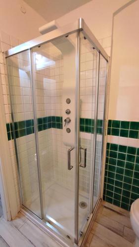 a shower in a bathroom with green and white tiles at claire de lune in Cagliari