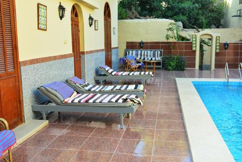 a row of lounge chairs next to a swimming pool at Villa Belzoni in Luxor