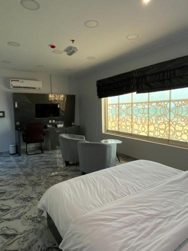 a bedroom with a bed and chairs and a television at مارينا للغرف الفندقية in Sohar