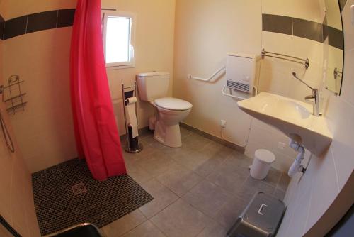 y baño con aseo, lavabo y cortina de ducha roja. en chalet le cedre, en Saint-Joseph-des-Bancs