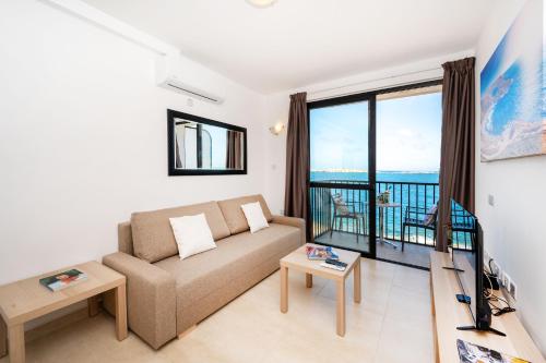 a living room with a couch and a large window at Islet Promenade Seafront Family Apartment with 2 balconies by Getawaysmalta in St. Paul's Bay