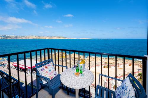 un tavolo e sedie su un balcone con vista sulla spiaggia di Islet Promenade Seafront Family Apartment with 2 balconies by Getawaysmalta a San Pawl il-Baħar