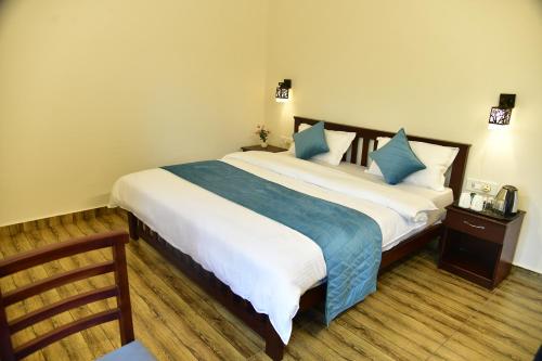 ラムナガルにあるCorbett wala by ayu villaのベッドルーム(青い枕の大型ベッド1台付)