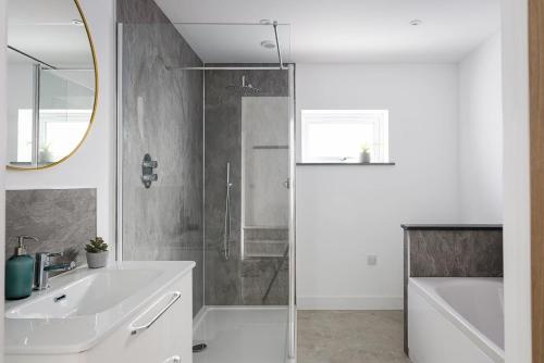 a bathroom with a shower and a sink and a mirror at The Hideaway, Modern 3 bed in Tintagel, Cornwall in Tintagel