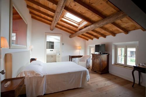 a bedroom with a white bed and wooden ceilings at Relais Corte Guastalla Apartments in Sona