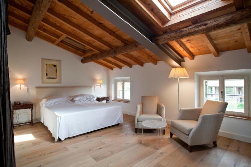 a bedroom with a white bed and two chairs at Relais Corte Guastalla Apartments in Sona