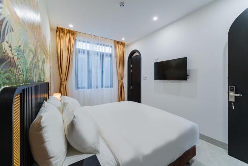 um quarto com uma cama branca e uma televisão em Q Boutique Hotel em Nha Trang