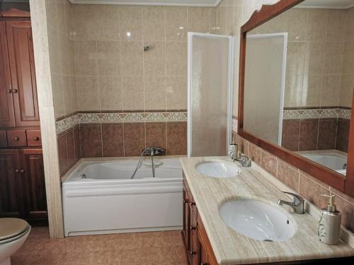 a bathroom with two sinks and a tub and a mirror at Apartamento en playa arenal de Burriana in Burriana
