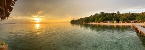 a sunset over a body of water with a beach at Reconnect - Private Island Resort & Dive Center Togean - Buka Buka Island in Ampana