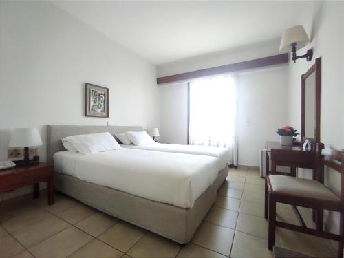 um quarto com uma grande cama branca e uma janela em Porfyris Hotel em Mandrákion