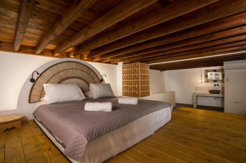 林都斯的住宿－Pera houses 2-bedroom in the center of Lindos，一间卧室设有一张带木制天花板的大床