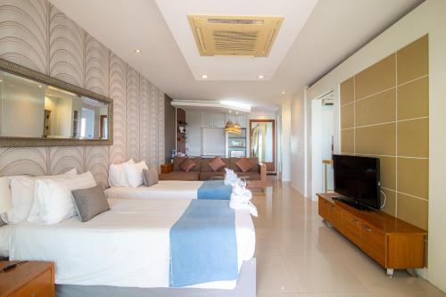 a hotel room with two beds and a television at Royal Beach View in Pattaya South
