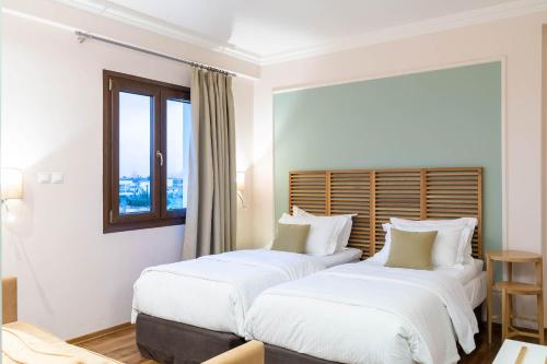 two beds in a hotel room with a window at Olympus Terra Boutique Hotel in Larisa