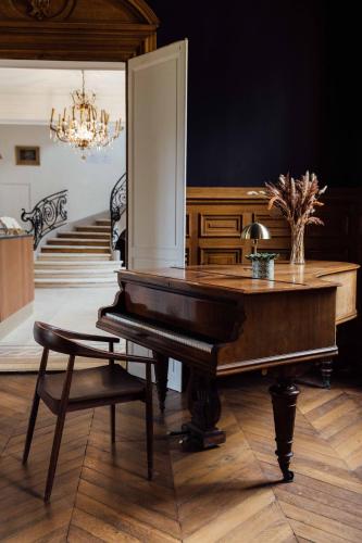 a piano in a living room with a chandelier at Château De La Bûcherie in Saint-Cyr-en-Arthies