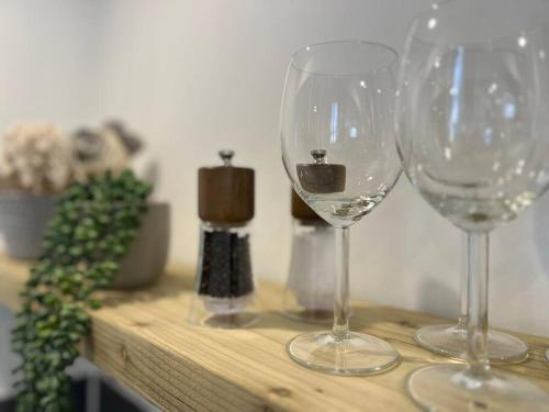 dos copas de vino sentadas sobre una mesa de madera en Cherry Blossom cottage, en Old Glossop