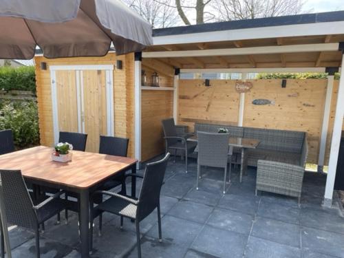 een patio met een tafel en stoelen en een parasol bij Chalet Lieblingsplatz in Lauwersoog