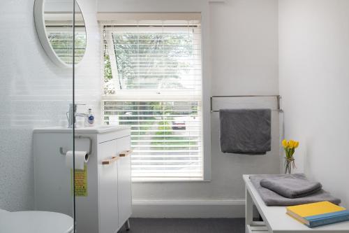 a white bathroom with a sink and a window at Bron Eryri - Our Cosy House opposite the entrance to Portmeirion! in Mynfford