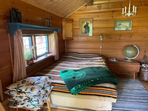 Un dormitorio con una cama en una cabaña de madera. en Idyllic Dalarna farmhouse at the lake, en Leksand
