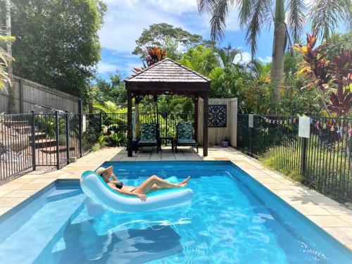 a woman laying on a raft in a swimming pool at The Junglehouse Noosa in Doonan