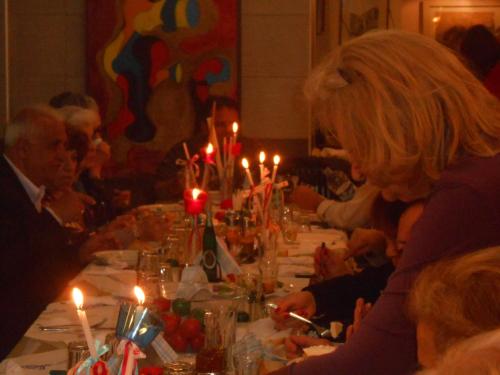 a group of people sitting at a long table with candles at Hotel Pegasos in Nikiana