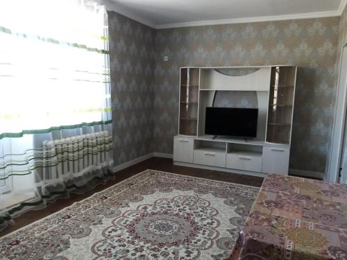 ein Wohnzimmer mit einem Flachbild-TV an der Wand in der Unterkunft Гостевой Дом in Qysylorda