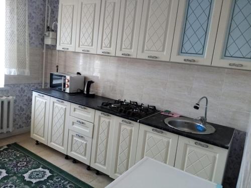 a kitchen with white cabinets and a sink at Гостевой Дом in Qyzylorda